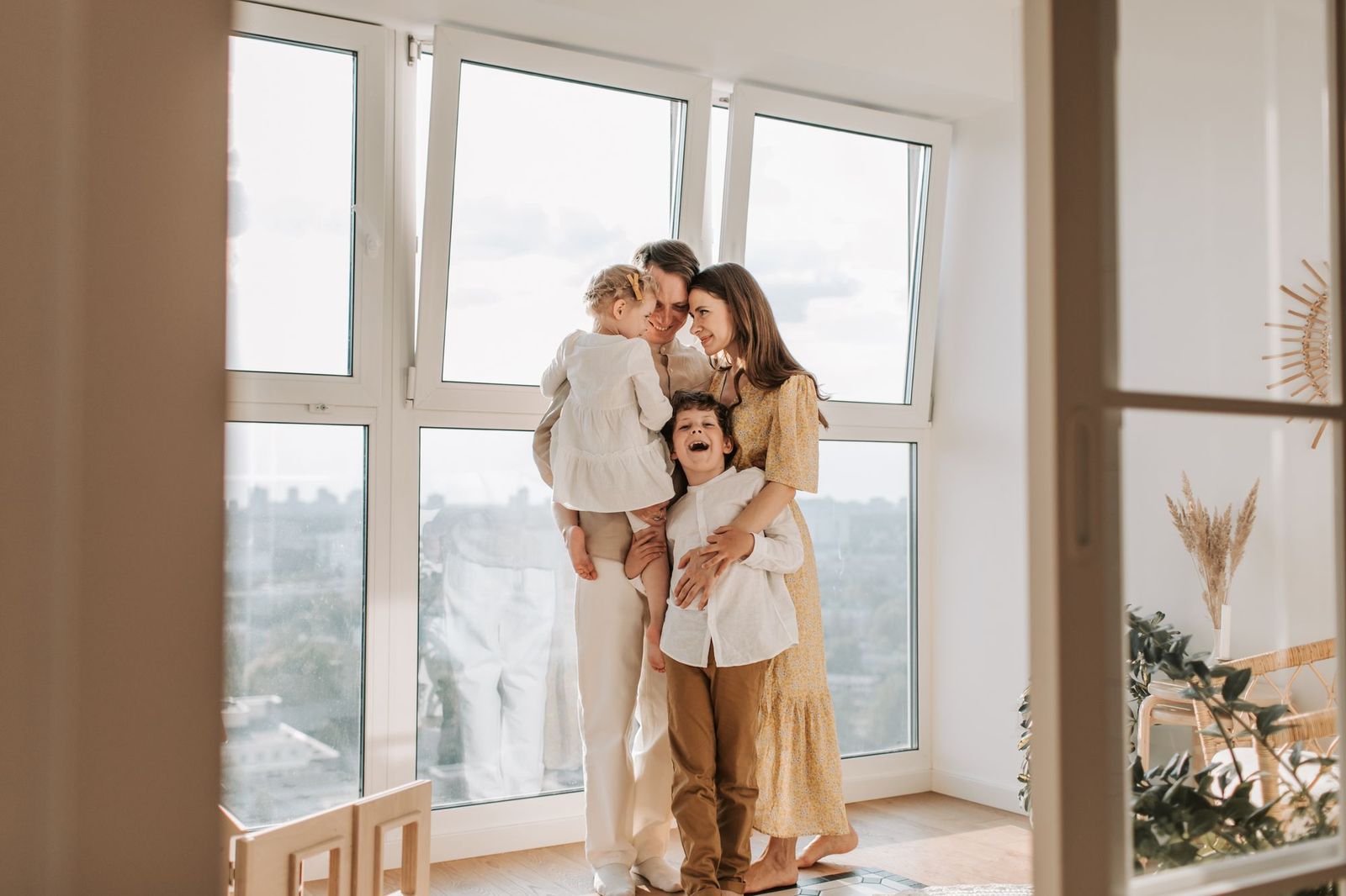 A happy family standing by a bright window at home