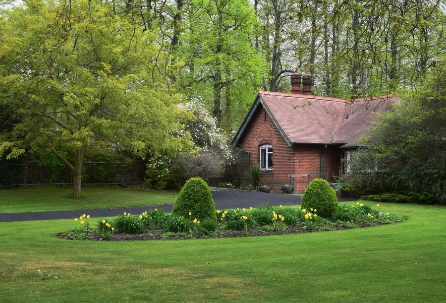 A brick house with a green lawn and garden